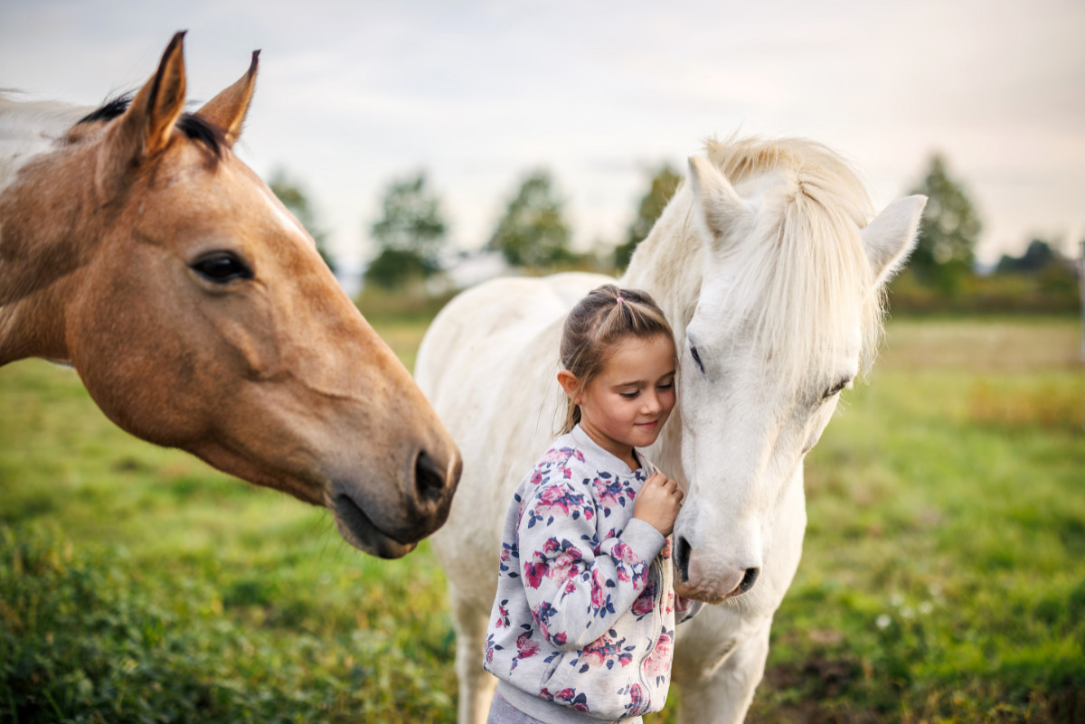 Kind steht vertrauensvoll neben einem Pony